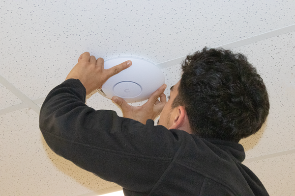 Ubiquiti installer deploying a UniFi access point in a business office