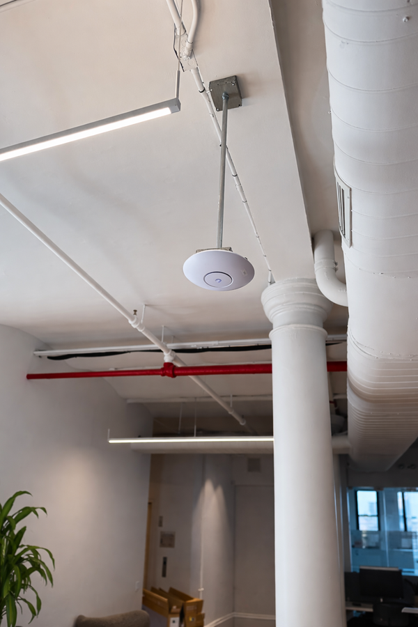 Ceiling-mounted Ubiquiti UniFi access point installed with conduit in a commercial office environment